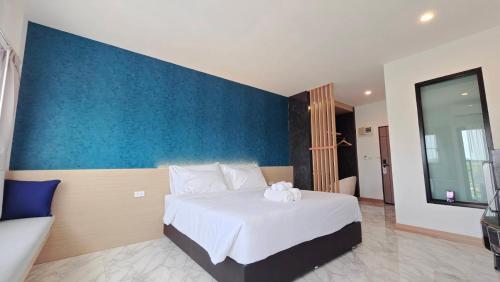 a bedroom with a large white bed with a blue wall at One Sakon Nakhon Hotel in Ban Na Weng