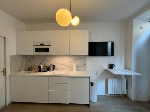 une cuisine blanche avec un évier et un micro-ondes dans l'établissement St Germain-Bon Marché - cosy n°1, à Paris