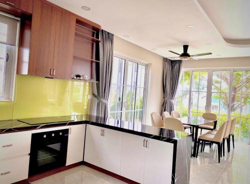 a kitchen with white cabinets and a table with chairs at Novaworld Phan Thiết - Villa Song Huong in Bình Tú