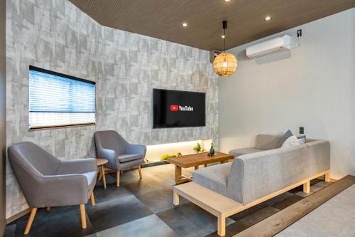a living room with two chairs and a couch and a tv at JAPAVISTA Yamato in Osaka