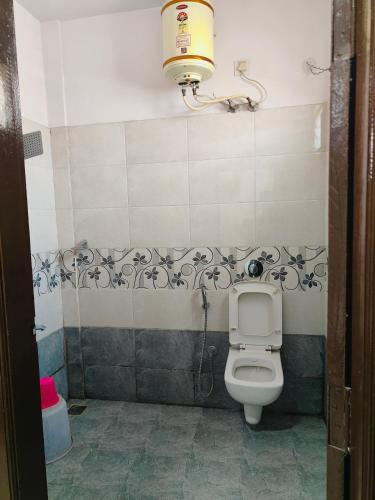 a bathroom with a toilet with a light above it at Hotel golden arch in Bengaluru