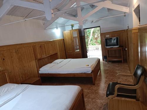una camera con due letti e una tv di Trilan Cottages - Donnington Road a Kotagiri