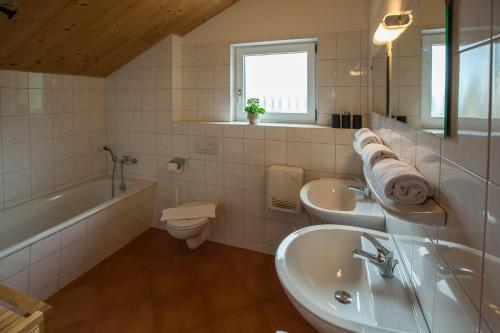 a bathroom with two sinks and a tub and a toilet at Alpendorf Dachstein West by ALPS RESORTS in Annaberg im Lammertal