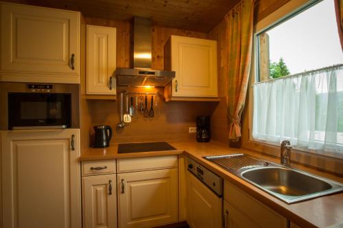 a kitchen with white cabinets and a sink and a window at Alpendorf Dachstein West by ALPS RESORTS in Annaberg im Lammertal