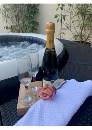 a bottle of wine and two glasses on a table at Appartement indépendant refait a neuf avec jacuzzi et terrasse privative proximité gare in Viarmes