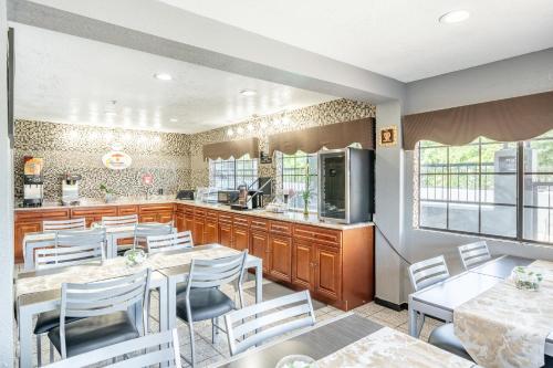 a kitchen with white chairs and tables in a restaurant at Super 8 by Wyndham San Antonio/Riverwalk Area in San Antonio