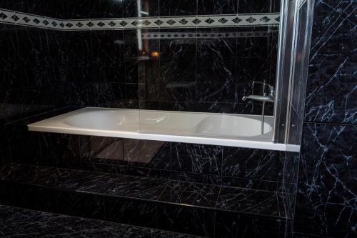 a bath tub in a black tiled bathroom at sand and sea in Póvoa de Varzim