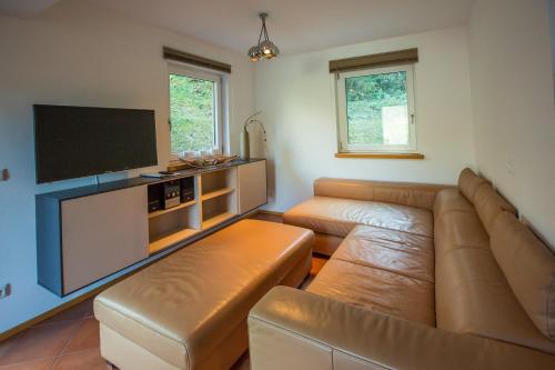 a living room with a couch and a flat screen tv at Alpendorf Dachstein West by ALPS RESORTS in Annaberg im Lammertal