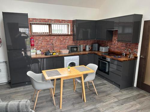 a kitchen with black cabinets and a wooden table and chairs at Flat in Eoropie, Ness, Isle of Lewis in Port of Ness