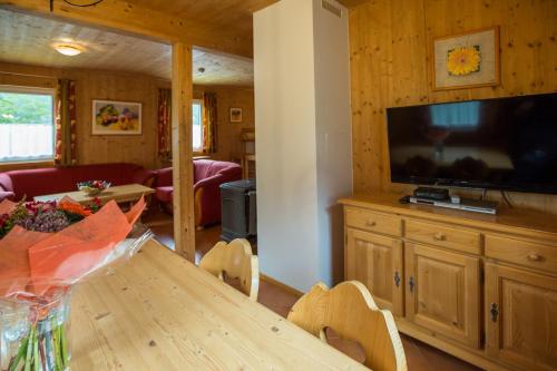 a living room with a table and a large television at Alpendorf Dachstein West by ALPS RESORTS in Annaberg im Lammertal
