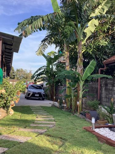 a car parked in the driveway of a house with palm trees at Sunshine guesthouse in Ban Saiyuan (1)