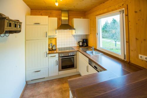 a kitchen with white cabinets and a sink and a window at Alpendorf Dachstein West by ALPS RESORTS in Annaberg im Lammertal