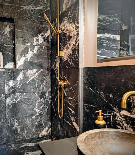 La salle de bains est pourvue d'un lavabo et d'un mur en marbre. dans l'établissement Chalet Petit Chappelle, à Chamonix-Mont-Blanc