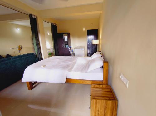 a bedroom with a large bed with white sheets and pillows at Rajbag Residency Guest House in Canacona