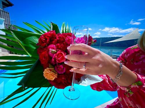 a woman holding a glass of wine next to a bouquet of flowers at Riviera 990 - Resort & Restaurant in Eşelniţa
