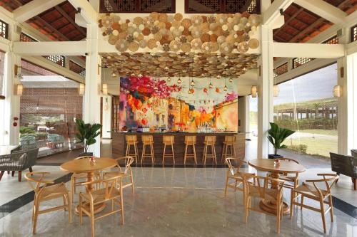 a restaurant with tables and chairs and a large painting at SBH Gloria Hue in Hue