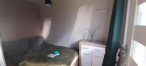 a small bedroom with a bed with a green curtain at OSADA POD LASEM in Andrychów