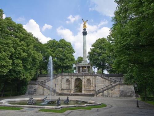a monument with a fountain in front of a building at TheGallery in Munich