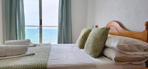 Un dormitorio con una cama con almohadas y una ventana. en Edifico Orbiplaya, en Torrevieja