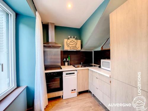 - une cuisine avec des murs bleus et des appareils blancs dans l'établissement Le Combolcha, à Murol