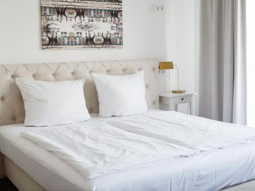 a white bed with white sheets and pillows at Les Nations in Berlin