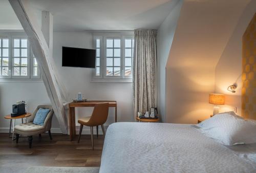 a bedroom with a bed and a desk and a chair at Auberge du Bon Laboureur Chenonceaux in Chenonceaux