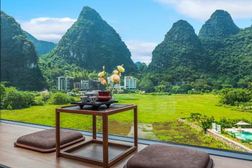 a room with a table with a view of mountains at Dyed Mount Boutique Hotel in Yangshuo