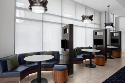 a waiting room with two tables and blue chairs at Courtyard Cleveland University Circle in Cleveland