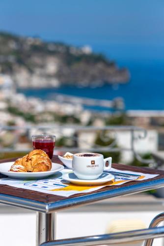 a table with a cup of coffee and a plate of food at Hotel Bel Tramonto in Ischia