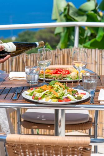 a table with a bottle of wine and a plate of food at Hotel Bel Tramonto in Ischia