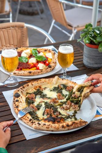 a table with two pizzas and two glasses of beer at Hotel Bel Tramonto in Ischia