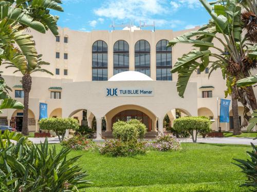 a building with palm trees in front of it at TUI BLUE Manar in Hammamet