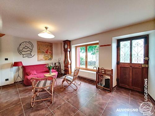 un salon avec un canapé rose et une table dans l'établissement Le Cantou de La Mouche, à Murol