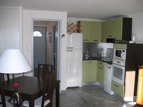 une cuisine avec des armoires vertes et un réfrigérateur blanc dans l'établissement appartement, climatisation, parking privée, terrasse, à Saintes-Maries-de-la-Mer