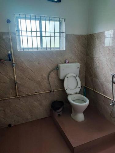 a bathroom with a toilet and a window at Greenwood Cabins Homestay, The Greenhouse in Jorhāt