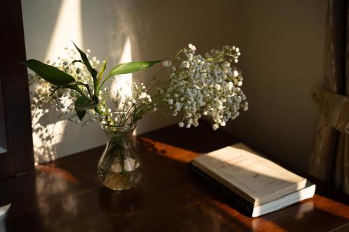 a vase of flowers and a book on a table at Mountain Pearl Hotel in Cat Ba