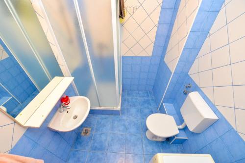 niebieska kafelkowa łazienka z toaletą i umywalką w obiekcie Apartment Dadi w Novalji