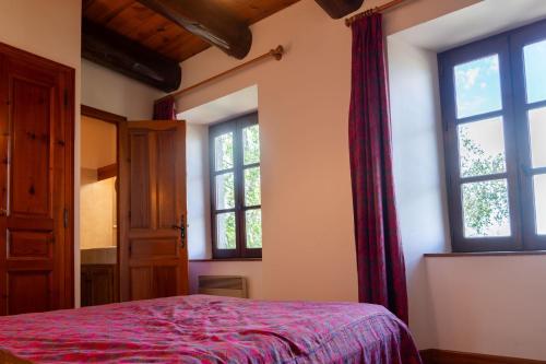 a bedroom with a bed and two windows at Gites de france au villard grand in Saint-Privat-du-Fau