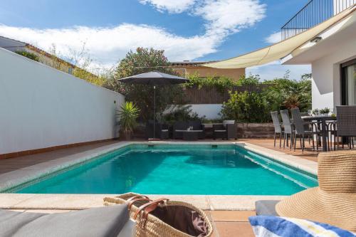 a swimming pool with a table and an umbrella at Casa Alexandra in L'Escala