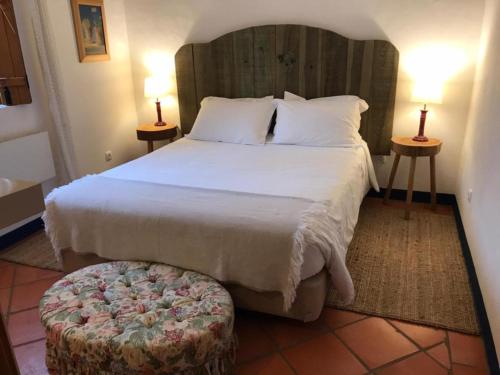 a bedroom with a large bed and a ottoman at Casas de Juromenha in Juromenha
