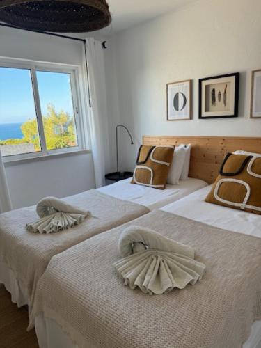 two beds in a white room with a window at Muramaris in Salema