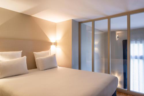 a bed with white pillows in a room with windows at Hôtel Helzear Etoile in Paris
