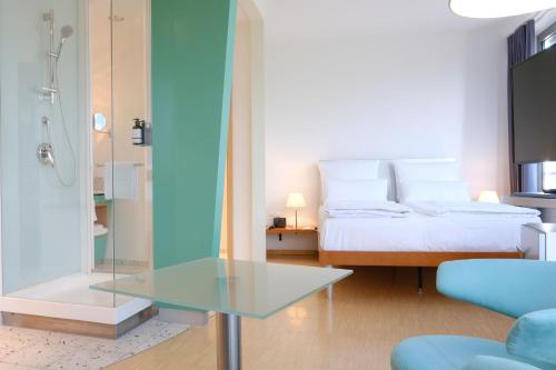 a bedroom with a bed and a glass table at FOUR Munich Neue Messe in Munich
