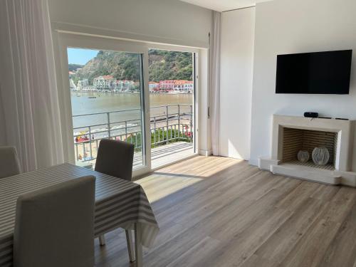 a living room with a table and a large window at Apartamento em frente à Praia in São Martinho do Porto