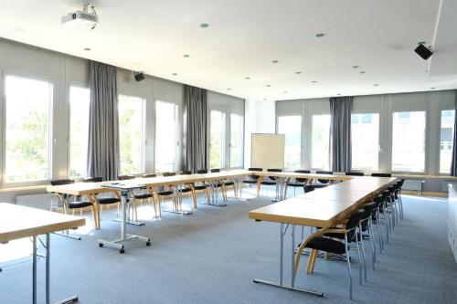 a large room with tables and chairs and windows at FOUR Munich Neue Messe in Munich