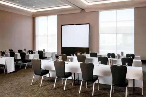a conference room with white tables and chairs and a screen at Sheraton Toronto Airport Hotel & Conference Centre in Toronto