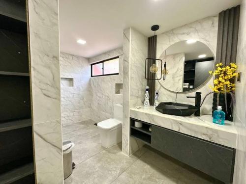 a bathroom with a sink and a toilet and a mirror at Mansión moderna Poblado-Piscina- in Medellín