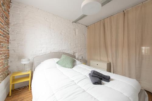 - un lit blanc dans une chambre dotée d'un mur en briques dans l'établissement Relais de la Gare - appartement traversant et calme, à Toulouse