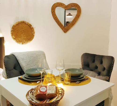 une table avec des assiettes et des verres et un cœur sur le mur dans l'établissement Maisonnette parking moto au cœur des sables, à Berck-sur-Mer