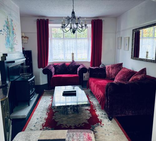 a living room with red couches and a table at Central City Centre 3 bedroom home Private Parking in Plymouth